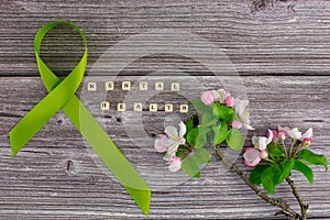 Lime green ribbon. Mental health awareness month concept mental health letters on old aged wooden background with