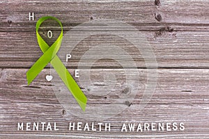 Lime green ribbon. Mental health awareness month concept mental health letters on old aged wooden background with photo
