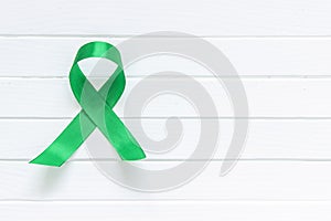 Lime Green Ribbon on white wooden background, world Mental health day. photo