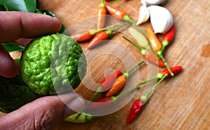Lime on hand for Tom yum with bamboo cutting board background