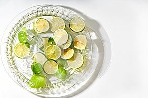 Lime and ice served in plate on white background with hard shadows