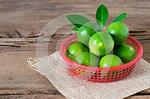 a Lime lemon in red bucket on rustic wooden background. copy spa