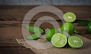 a Lime lemon with sack cloth on rustic wooden background.