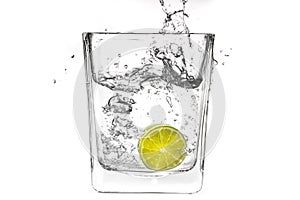 Lime slice falling in a glass of water