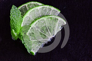 Lime slices and mint on slate background