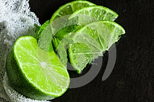 Lime, slices and mint with white cloth on slate background