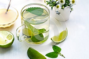 Lime tea with mint in a glass cup, honey and chamomile