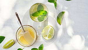 Lime tea with mint in a glass cup and honey on a white background