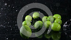 Limes falling with water on black background