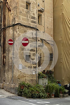 Limestone corner house with two traffic signs for wrong direction and pot plants, in Valetta, Malta
