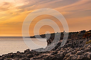 Limestone rock formation at sunset with Guia lighthouse on the horizon at Boca do Inferno, Cascais PORTUGAL