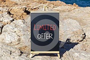 Limited offer symbol. Concept words Limited offer on beautiful black chalk blackboard. Beautiful stone sea blue background.
