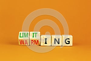 Limiting global warming symbol. Concept words Limiting and Warming on wooden cubes. Beautiful orange table orange background.
