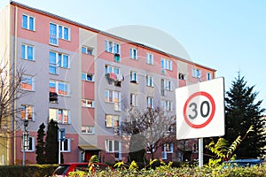Limiting the speed of vehicles in a residential area to 30. Road sign on the background of an apartment building in the summer.