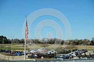 Limp American flag on flagpole over a parking lot.