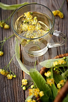 Linden flowers in a glass cup of tea on a wooden table