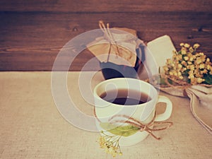 Linden tea and jar with honey decorated with linden flowers on canvas and wooden background