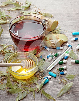 Linden tea on wooden table. a cup of linden tea, honey, ginger, thermometer and tablets. traditional remedies for colds and flu.