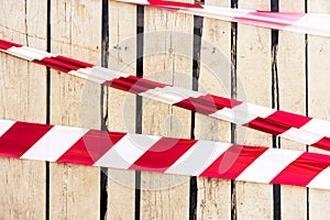 Line of barrier signal red and white tape warning tape used for hazards and awareness set against on the background of a wooden wa