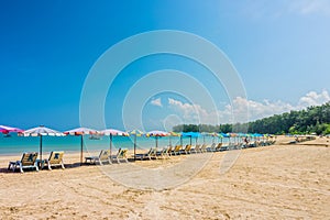 Line of beach umbrellas and sunbathe seats on Phuket sand beach