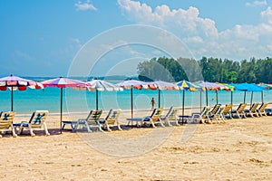 Line of beach umbrellas and sunbathe seats on Phuket sand beach