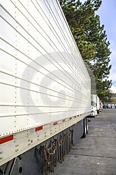 Line of big rigs semi truck with different semi trailers standing on the truck stop