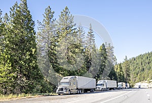 Line of the big rigs semi trucks with semi trailers standing on the road shoulder for truck drivers rest