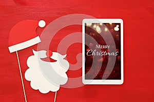 On line christmas holiday shopping concept. Santa claus red and beard hat next to tablet device