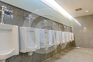 Line of clear white urinals in public toilets man