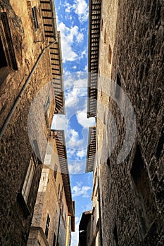 Line of cloudy blue sky bitween stone ancient biuldings in a narrow street photo