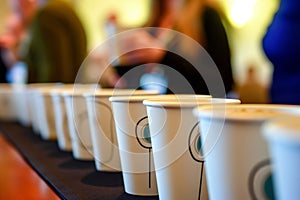 line of coffee cups ready for conference break, attendees in line