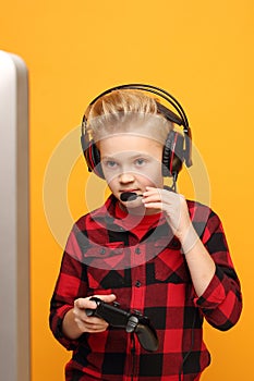 On-line computer game. A young boy plays on the console with headphones.