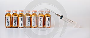 Line of coronavirus covid-19 vaccine vials and medical syringe with needle up on white background. Banner for advertising of