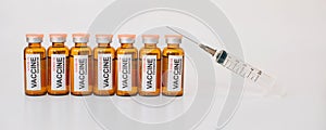 Line of coronavirus covid-19 vaccine vials and medical syringe with needle up on white background. Banner for advertising of