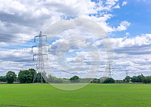 Line of Electricity Pylons in Green Field
