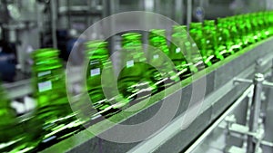 line for filling beer in a brewery. Empty green glass bottles moving on a conveyor belt in a queue at a beer factory.