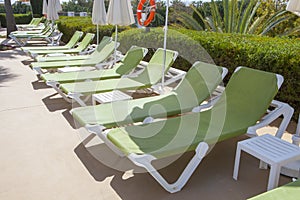 Line of green sunloungers on swiming pool photo