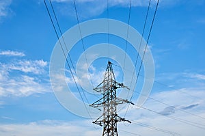 A line of high-voltage cables against a blue sky with clouds.