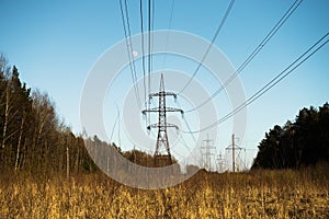 A line of high-voltage pillars through a plowed agricultural field