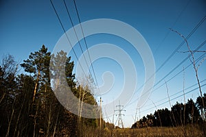 A line of high-voltage pillars through a plowed agricultural field