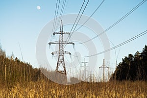 A line of high-voltage pillars through a plowed agricultural field