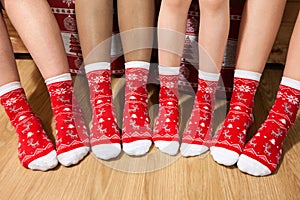 Line from human feet wearing red Christmas socks, adults and children legs together