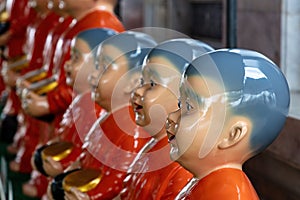 Line of monk statues, Wat Rakhang Bangkok. Red robes, bowls, shaved heads.