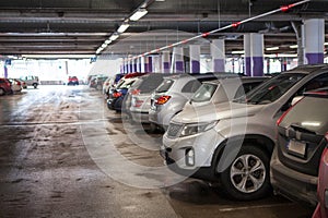 Line of a multistorey parking ramp full of parked cars, red light above each place photo