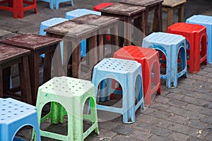 Line of plastic chairs with blur wooden table on Asian street. Concept of drinking tea, coffee and having fast food outdoor