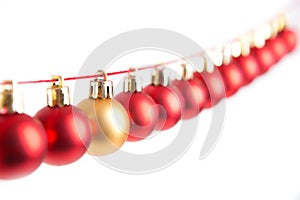 Line of red christmas balls and one gold or yellow ball on white background. Christmas decorations.