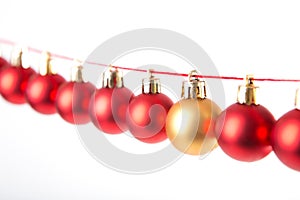 Line of red christmas balls and one gold or yellow ball on white background. Christmas decorations.