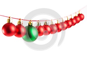 Line of red christmas balls and one green ball on white background. Christmas decorations.