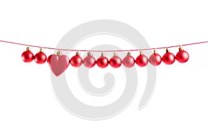 Line of red christmas balls and one heart shape christmas bauble on white background. Christmas decorations.