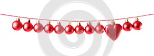 Line of red christmas balls and one heart shape christmas bauble on white background. Christmas decorations.